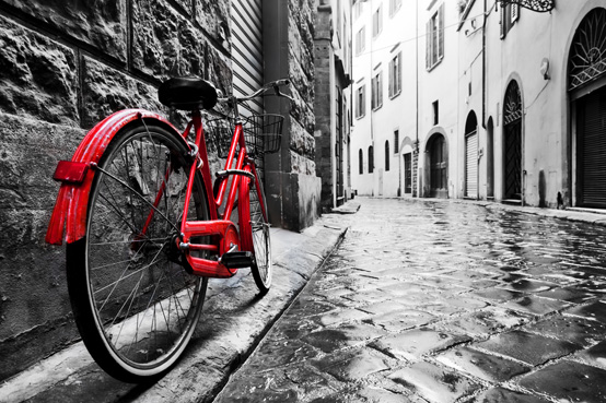 אופניים אדומים וינטג' רטרו ברחוב מרוצף אבן בעיר העתיקה.צבע בשחור לבן.קונספט אופניים מקסים ישן.